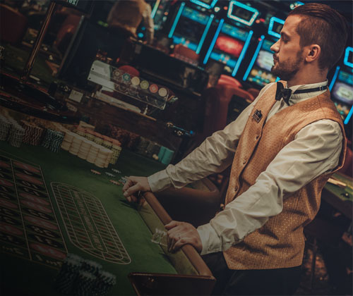 Dealer behind table in a casino.